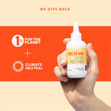 Hand holding the bottle, we give back graphic with 1% for the Planet and Climate Neutral logos