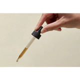 Hand holding glass dropper of brown olive leaf extract