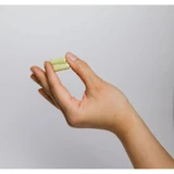 Hand holding a single green capsule