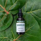 Dandelion dropper bottle resting against large green leaves