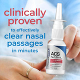 Hand holding an ACS Nasal spray bottle on a blue background