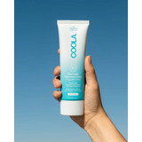 Hand holding the Coola Mineral Body Lotion SPF 50 tube