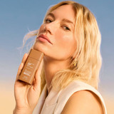 Blonde woman holding the Sunless Tan SPF 50 bottle
