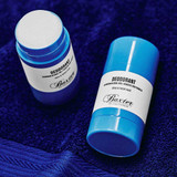 Two Baxter of California Deodorant sticks on a navy towel, one uncapped