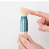 Hand tapping a Brush-on Shield brush to release powder