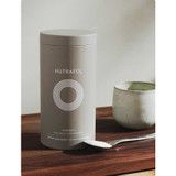 Nutrafol +Strength Collagen canister on a wooden table with a scoop and mug
