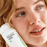 Smiling woman holding the Clear Start foaming wash to her cheek