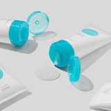 Several Obagi360 Exfoliating Cleanser tubes scattered on gray with open caps