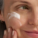 Woman with cleanser lather on her cheek