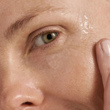 Close-up of model's eye area with fingertip applying Dermalogica MultiVitamin Power Firm