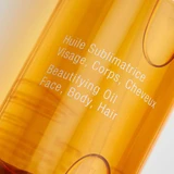 Close-up of the golden oil bottle with face, body, hair text