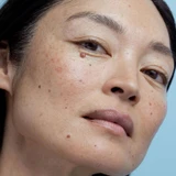 Close-up of freckled model's face on blue background