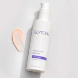 Glytone Mild Cream Cleanser bottle lying beside a peach cleanser swatch