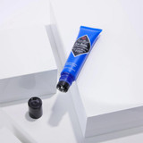 Eye Balm tube lying on white blocks with its cap off