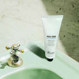 Baxter of California Facial Scrub tube on a green bathroom sink