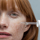 Model applying Obagi Professional-C Serum to cheek with glass dropper
