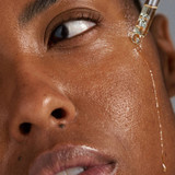 Oil dripping from a dropper down a woman's cheek
