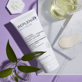 Replenix Retinol body lotion tube with a lotion swatch and green leaves on a marble tray