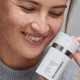 Smiling woman holding PowerBright Overnight Cream near her face