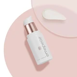 Emepelle Eye Cream bottle lying on a pink dish with a cream swatch