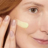 Woman with a swipe of pale yellow retinol serum on her cheek