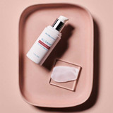 Serum bottle and a smear of serum on a pink tray