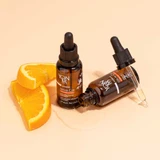 Two YonKa Serum C20 bottles with orange slices on a peach background