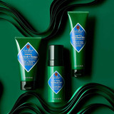 Jack Black scalp scrub tubes and a bottle on a dark green background
