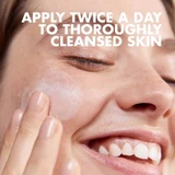Smiling woman applying cream with apply twice a day text