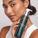 Woman holding the cleanser bottle to her cheek