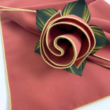 Add a Burnt Orange with Gold Trim Napkin Carole Shiber Designs, a decorative linen napkin featuring a burnt orange color with elegant gold trim edging, styled with a rolled flower design and incorporated green and gold leaves.