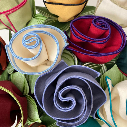 Wild Mis-Matched Napkin Bouquet, colorful fabric napkins artfully folded into rose shapes arranged together with green leaves, designed by Carole Shiber Designs. Wild Mis-Matched Napkin Bouquet, colorful fabric napkins artfully folded into rose shapes arranged together with green leaves, designed by Carole Shiber Designs.