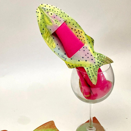 Fish are Jumping! Napkins & Rings Carole Shiber Designs, decorative napkin holder shaped like a fish with colorful and whimsical design, placed in a wine glass with pink napkins inside.