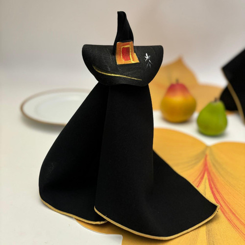 Witch-Crafty Napkin Doll, black fabric napkin folded into a witch with a painted black hat and orange buckle detail, used as a decorative Halloween or witch-themed table centerpiece.