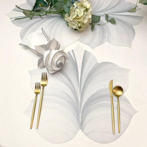 Add a 5 Point Fountain Leaf - White with Silver Placemat Carole Shiber Designs, decorative placemat with a white and silver fountain leaf design, complemented by gold utensils, with floral decoration.