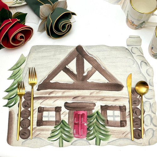 Add a CAROLE'S CABIN Placemat, a hand-painted wooden cabin design with pine trees, red door, and window details. Also, decorated with gold cutlery and holiday-themed napkins and mugs.