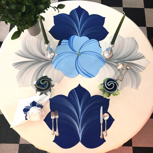 7 Point Leaf - Dark Blue/Frost Carole Shiber Designs, table setting with large blue and frosted leaf-inspired placemats and matching napkins, silver cutlery, green candles, and floral accents.