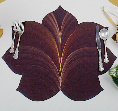 7 Point Leaf - Eggplant/Gold & Bronze Carole Shiber Designs, a decorative table placemat resembling a stylized leaf in deep eggplant, gold, and bronze colors, paired with silver cutlery.