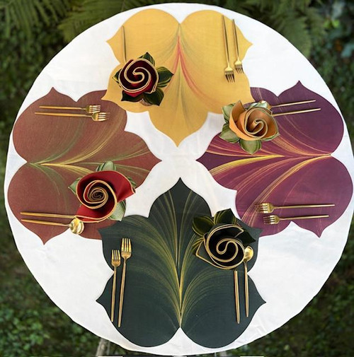 Jeweltone Fountain Leaf Placemats, Set of Four Carole Shiber Designs featuring colorful leaf-shaped placemats with decorative paper roses and gold cutlery for a stylish dining setup.