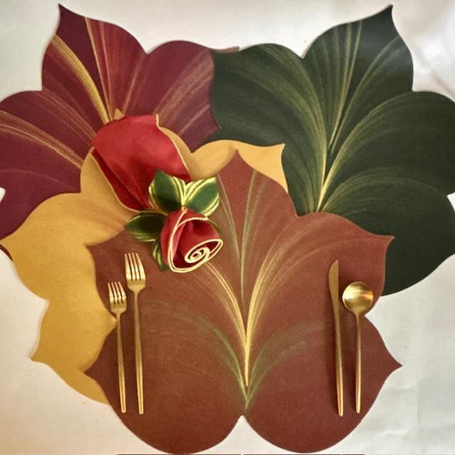 Autumn 4 Leaf Placemats, fall-themed placemats with large colorful leaf designs in green, yellow, red, and brown, arranged on a table with gold utensils and a decorative rose napkin.