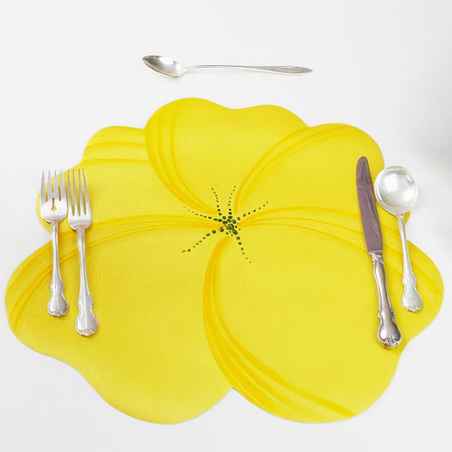 Buttercup Placemat - Yellow, a bright yellow floral-shaped placemat with a detailed black dotted center, used as tableware setting with silverware on a white background.