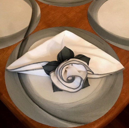Custom Napkins Builder Carole Shiber Designs, elegant folded napkin with black and white color scheme and decorative floral design.
