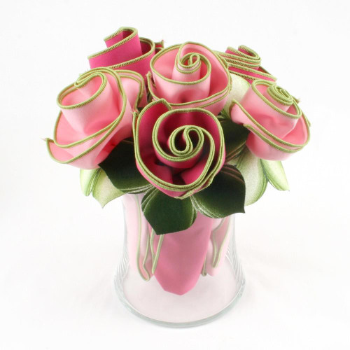 Assorted Pinks Napkin Bouquet Carole Shiber Designs, a floral arrangement of pink fabric napkins folded into rose shapes with green trim, arranged in a clear glass vase.