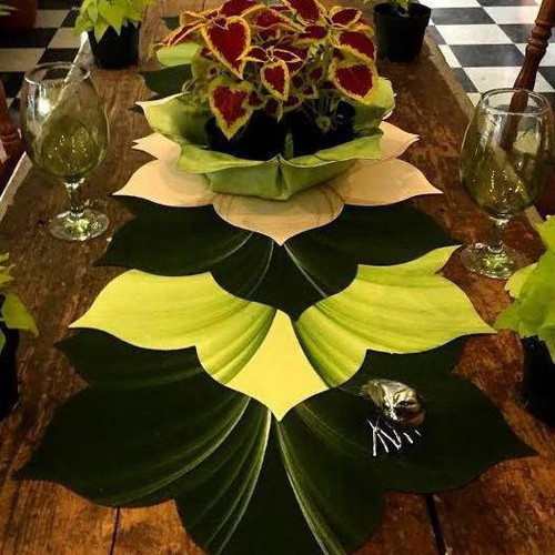 Interlocking Leaves, S/6 Carole Shiber Designs - Decorative leaf-shaped table centerpiece with large green and yellow leaves surrounding a potted plant with colorful foliage on a wooden table.