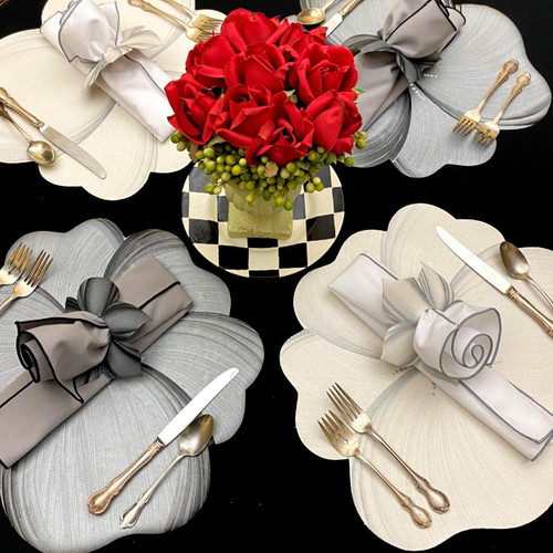 Grey & Buttercream Buttercups 4 Set Carole Shiber Designs, elegant table setting with cream and grey flower-shaped placemats, gold cutlery, and decorative napkins with bows, centered by a bouquet of red roses and green berries in a black and white checkered vase.