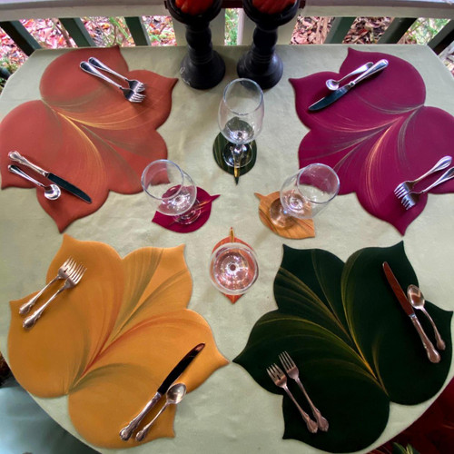 Hand-Painted Sweet Leaf & Coaster Set/4 Carole Shiber Designs, colorful leaf-shaped coasters with tableware and wine glasses arranged on a table.