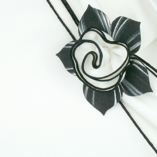White with Black Trim Napkin Carole Shiber Designs, a decorative napkin with a black and white ribbon flower embellishment.