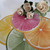 SALE! Artisanal Citrus Slice Placemats, colorful hand-painted citrus slice vinyl sponge-clean placemats shown with a bouquet of ivory rose napkins, not included, on top.