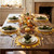 Wild Sunflower Placemat by Carole Shiber, autumn-themed dining table setting with decorated pumpkins and lit candles.