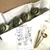 Garden Greens Bouquet Carole Shiber Designs, a floral arrangement featuring rolled green ribbons resembling roses, accompanied by decorative leaves inside a white box with tissue paper.